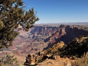 Colorado River shown as distant ribbon below sculptured the colorful mahogany rock cliffs.