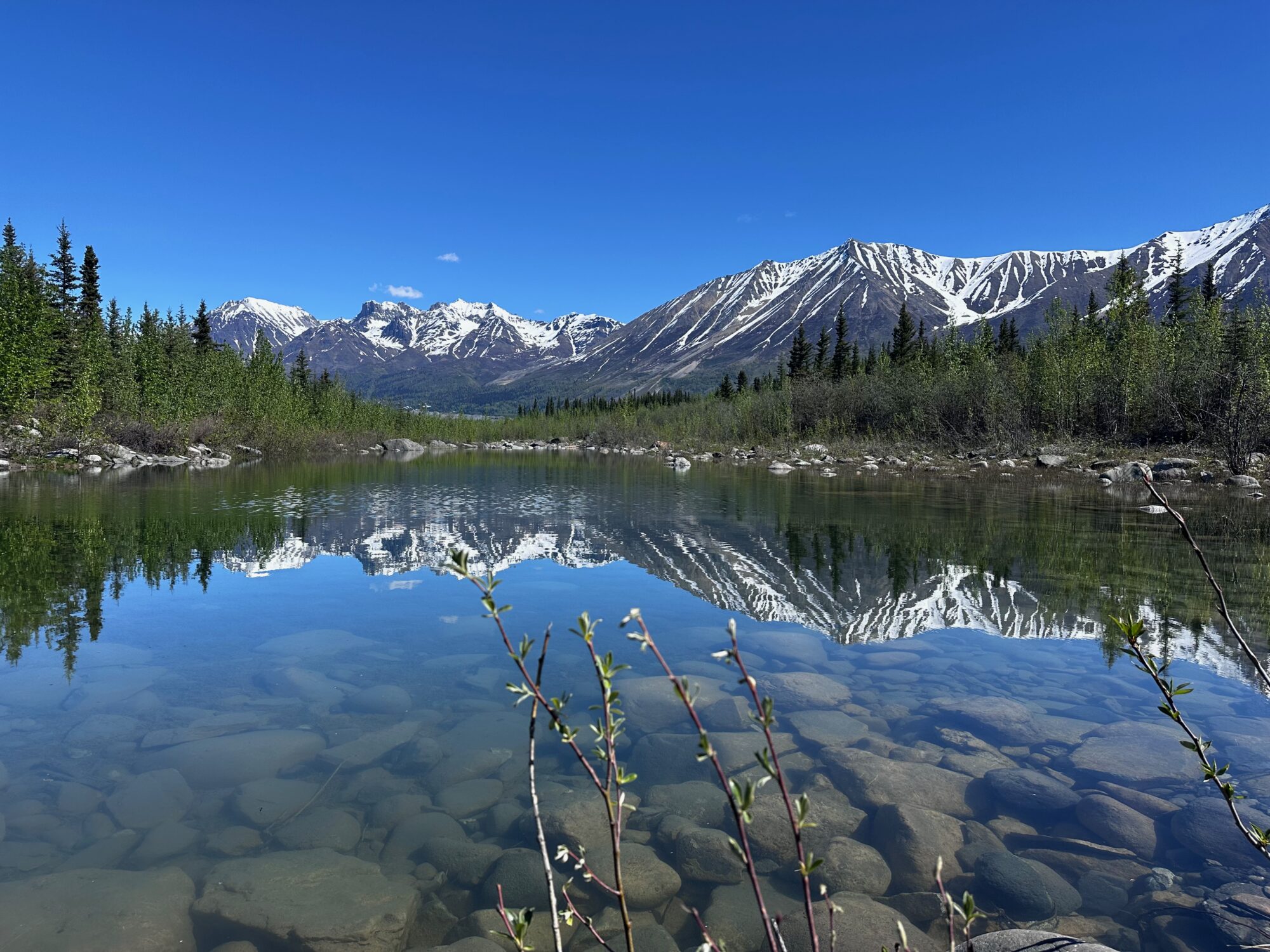 A crystal clear lake reflecting the snnow-capped mountains of Wrangell-St Ellis.